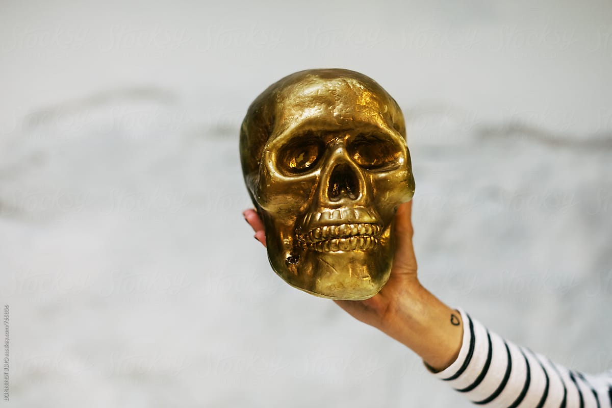 Hand holding a gold skull.