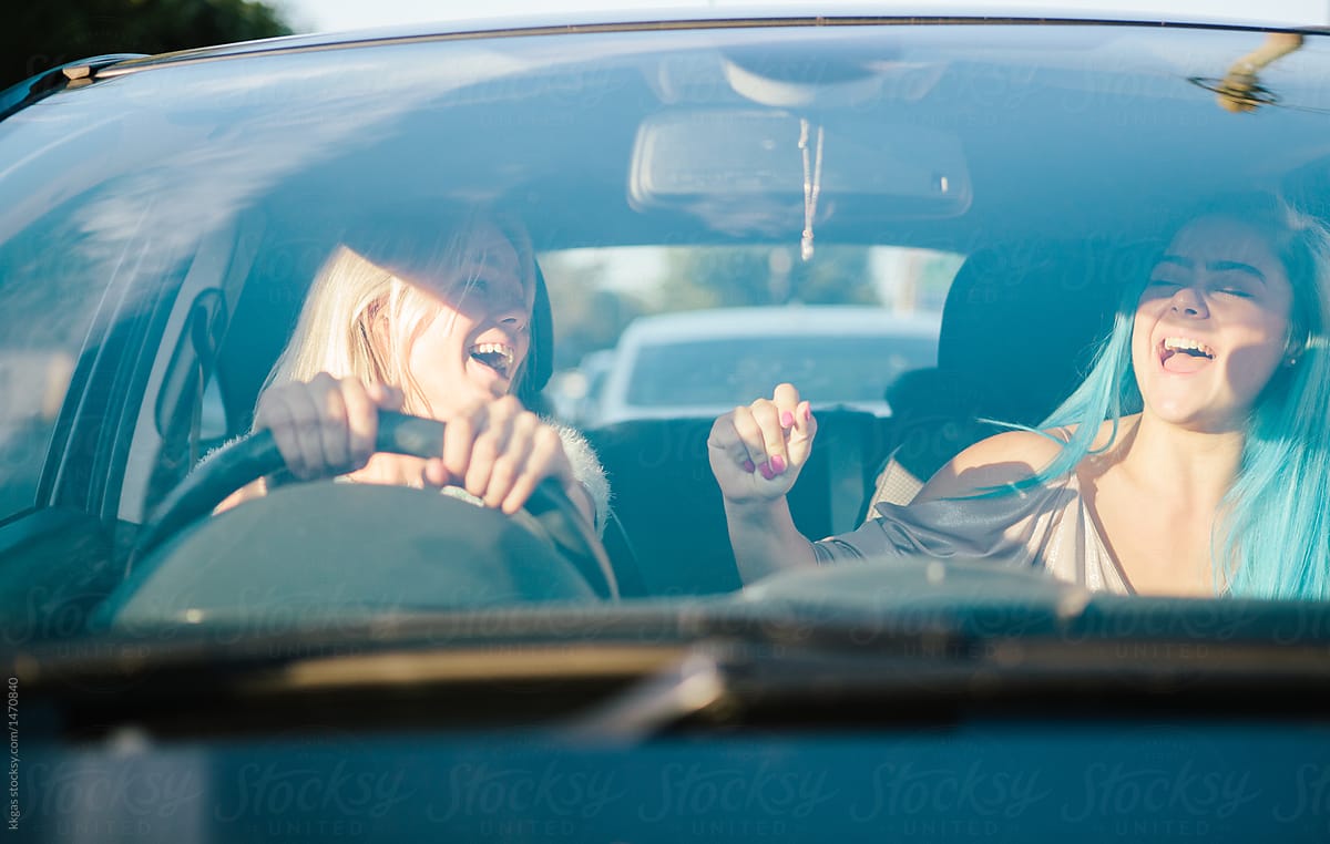 Young women singing along to music in their car