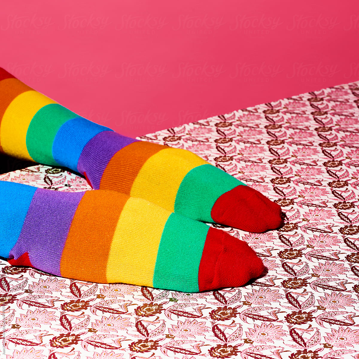 man wearing rainbow patterned socks in his hands
