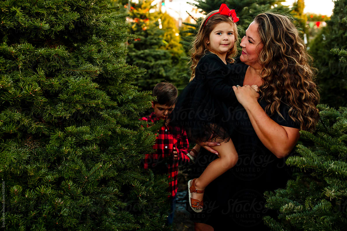 Mother and daughter in front of pine trees with brother behind them