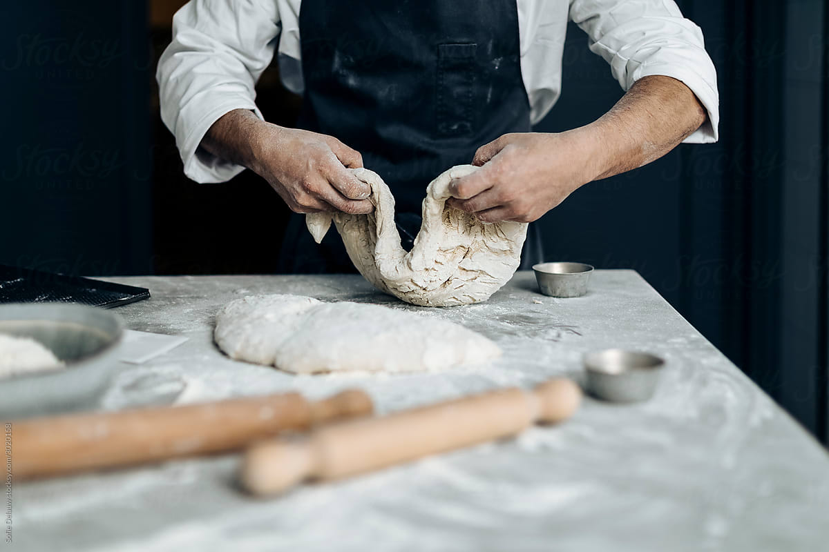 Crop baker preparing dough in kitchen