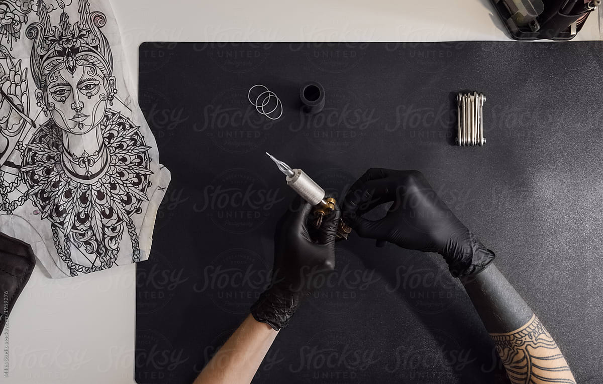 Crop tattoo artist preparing machine