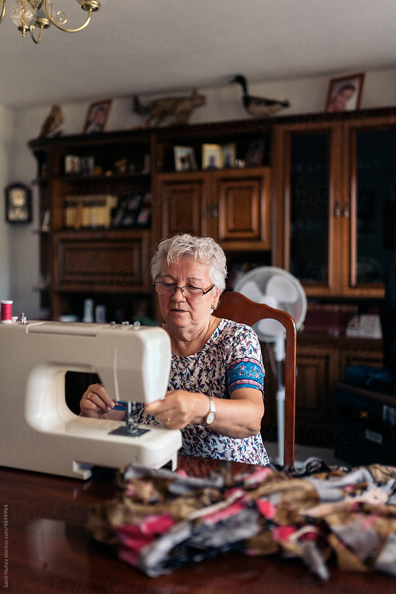 Senior seamstress sewing on machine