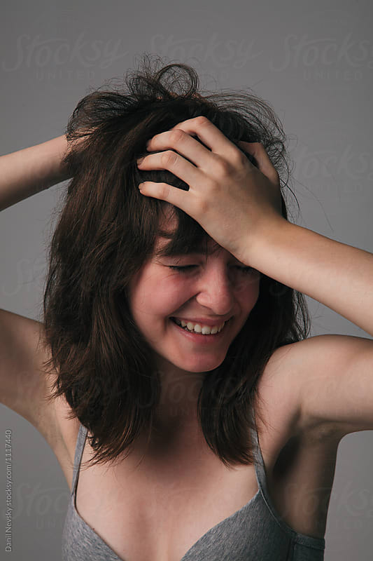 Young laughing woman with messy hair in grey bra