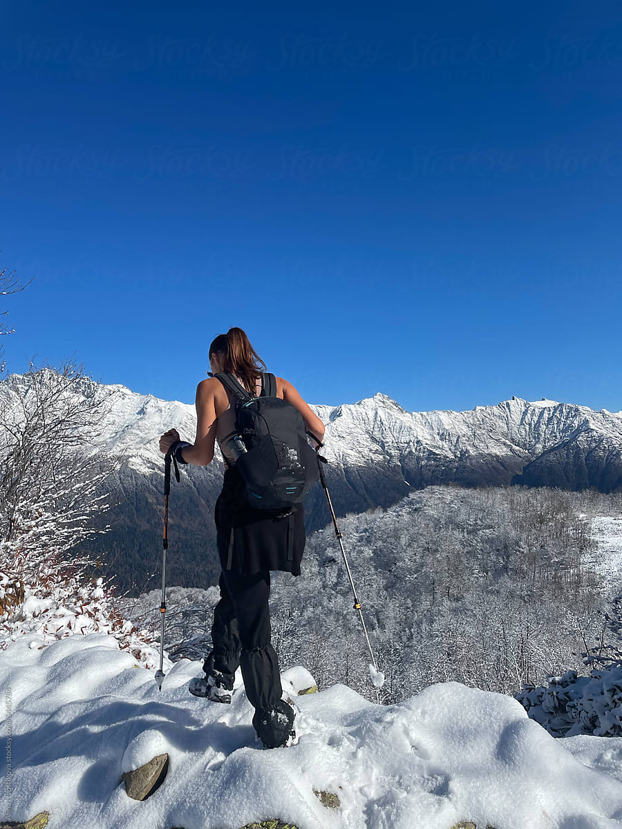 Woman with trekking poles on snowy mountain slope