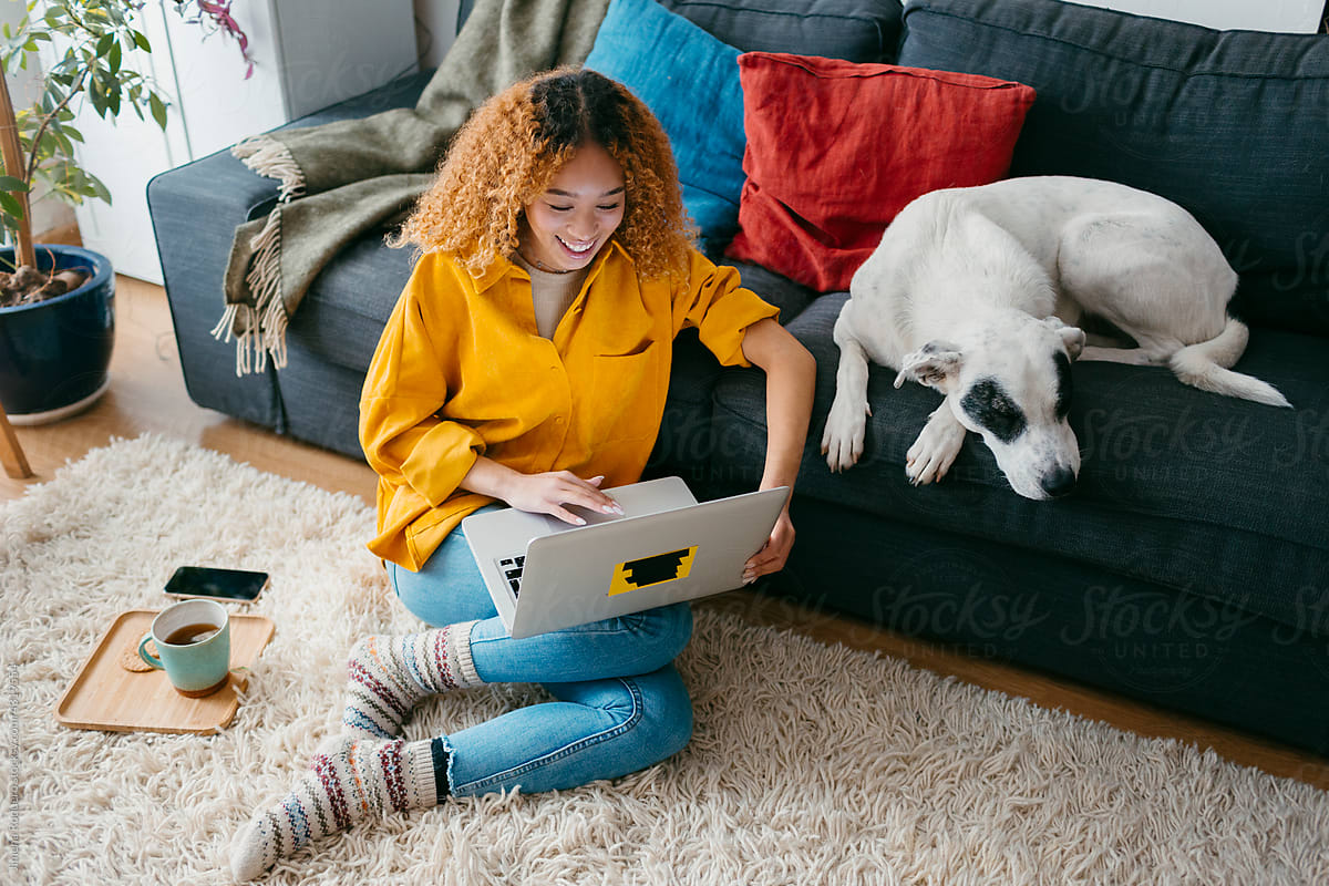 Teenager at home living room using laptop with dog