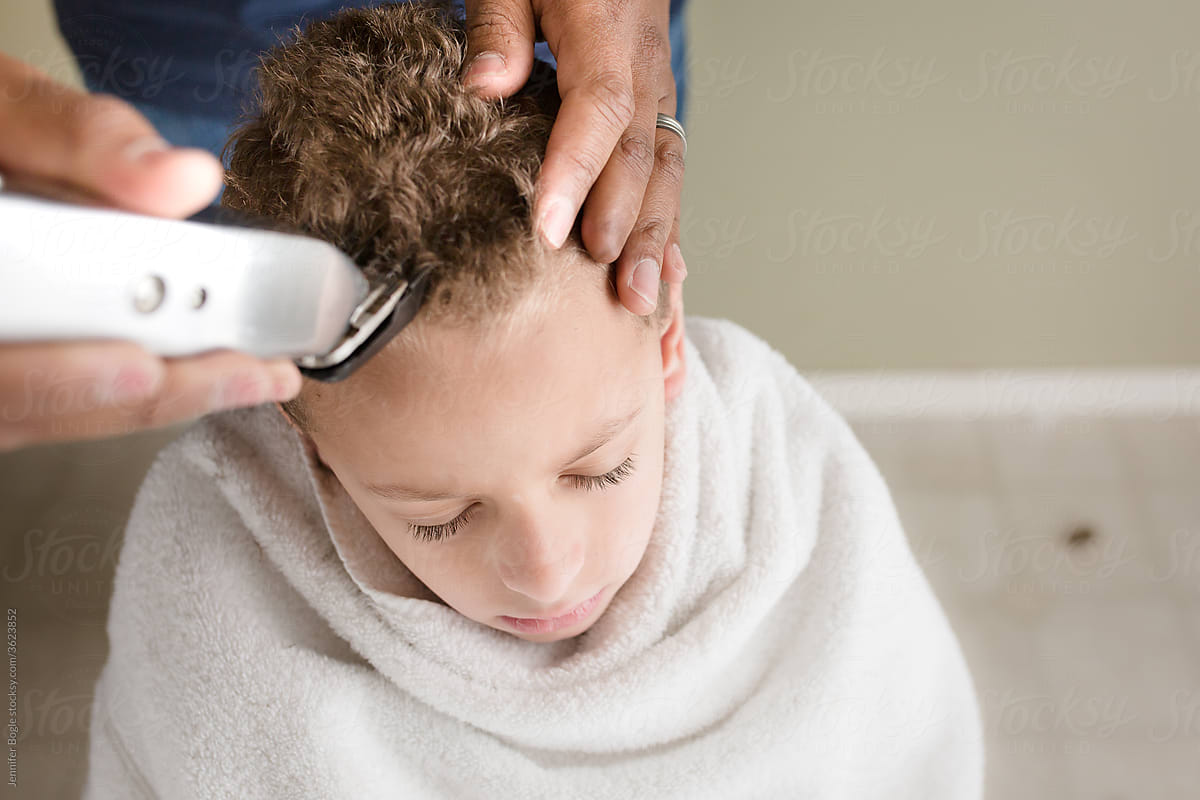 High angle view of father cutting son\'s hair with clippers