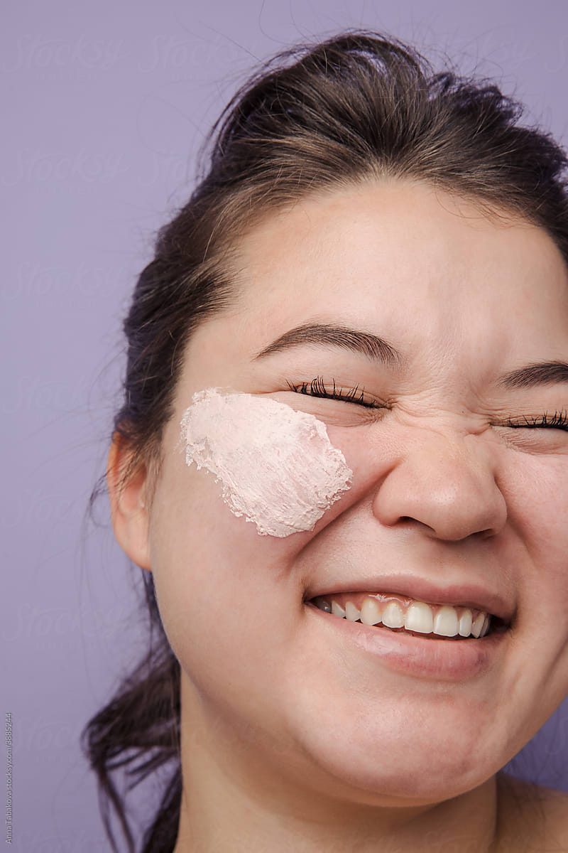 East asian model with pink cream on her face smiling
