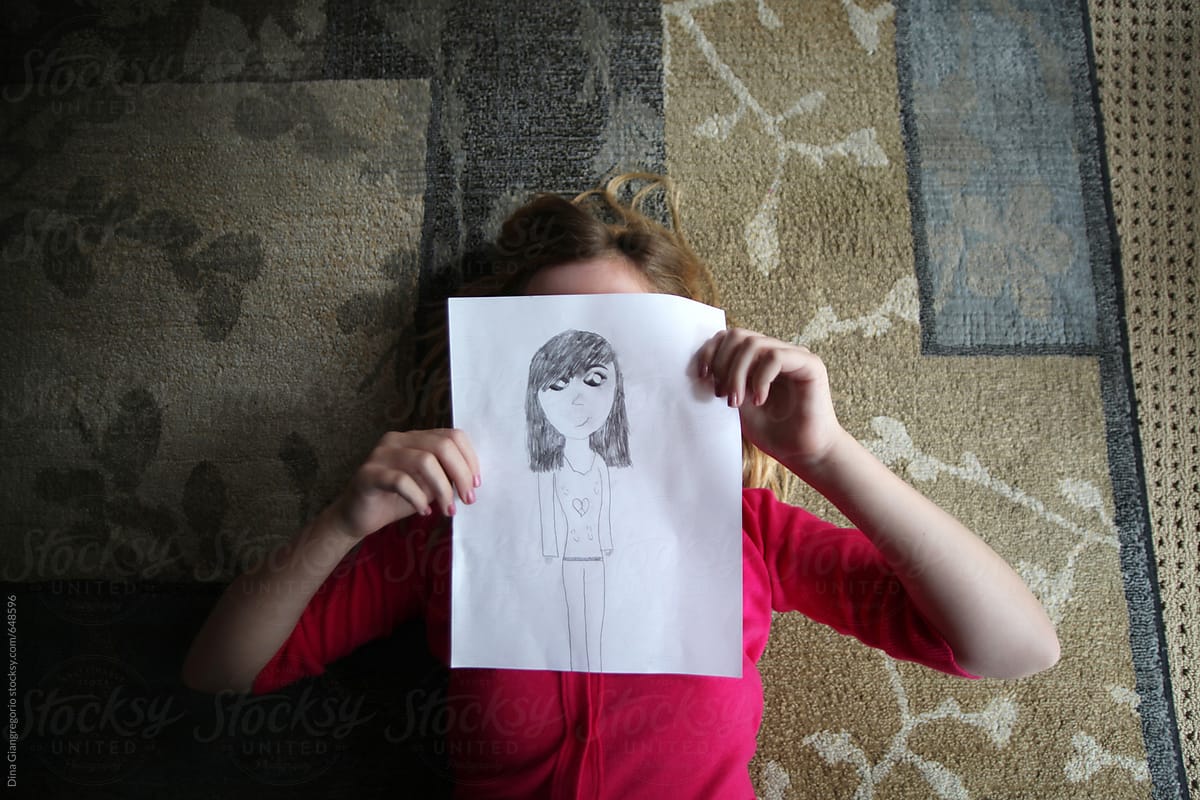 Young Girl Covering Her Face With A Drawing By Stocksy Contributor