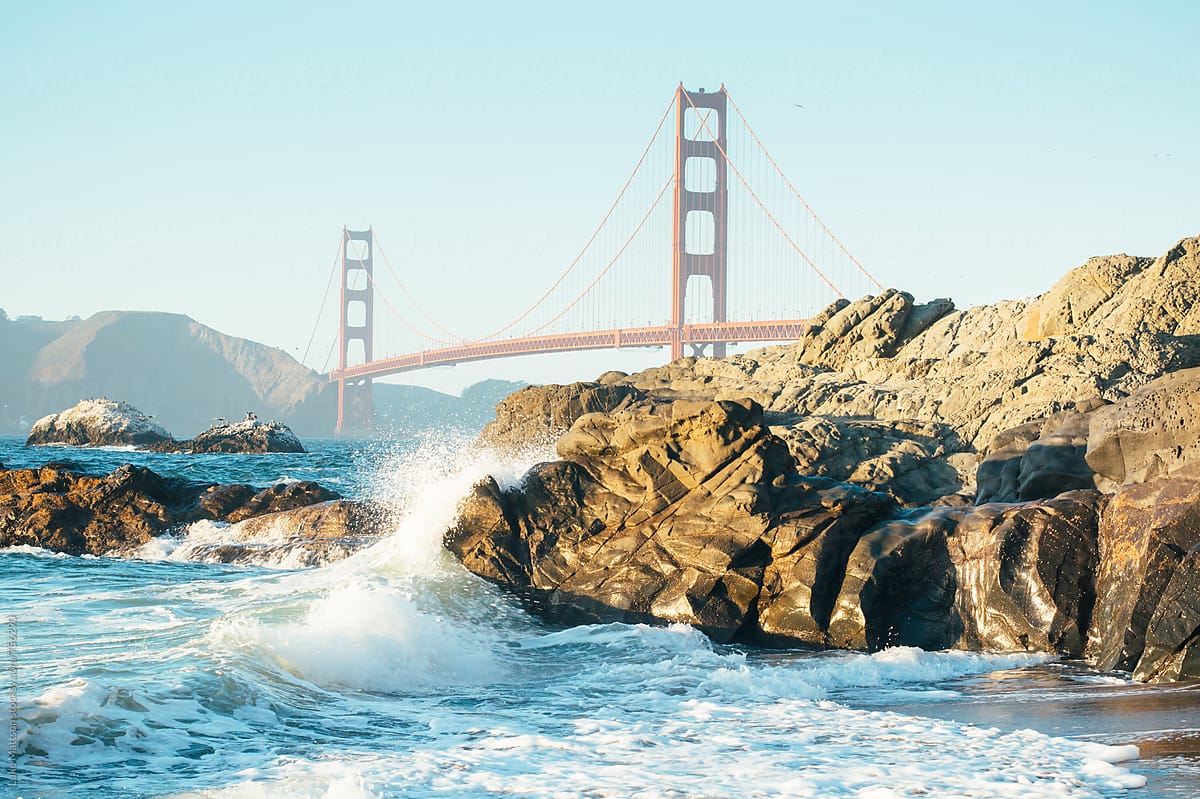 View Of Golden Gate Bridge From Baker Beach With Waves Splashing Against Rocks