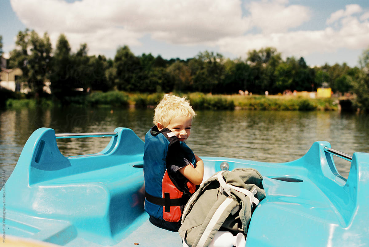Toddler boy with life jacket in a pedalo boat enjoying summer