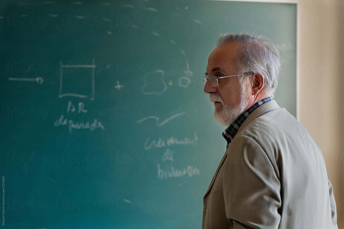 Mature professor in a classroom with green chalkboard