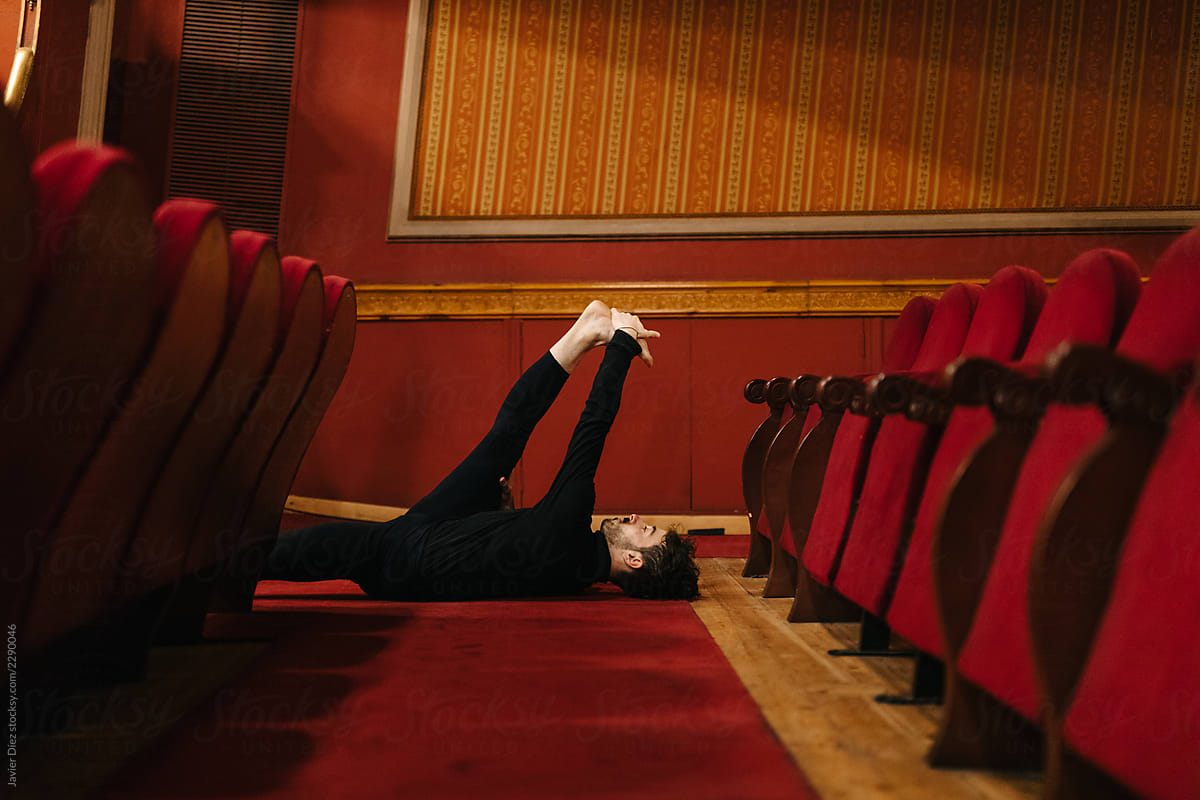 Male dancer stretching on theatre floor