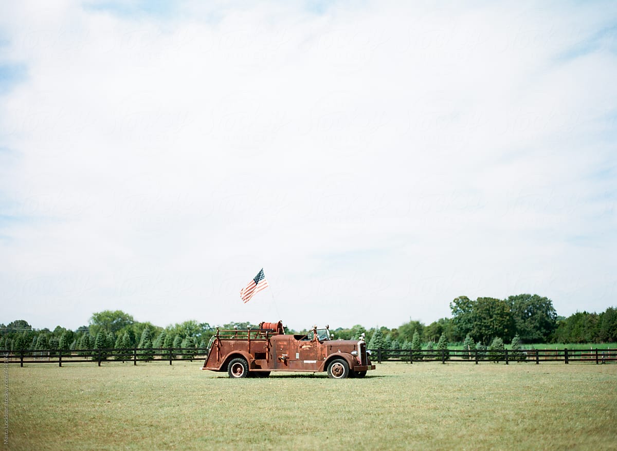 Old red and rusted fire truck with an American flag on a Christmas tree farm