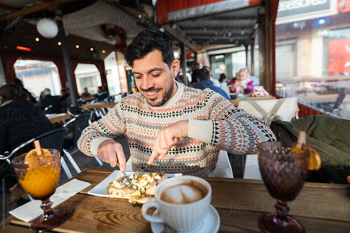 Cheerful smiling man eating food in a cafe, drinking coffee.