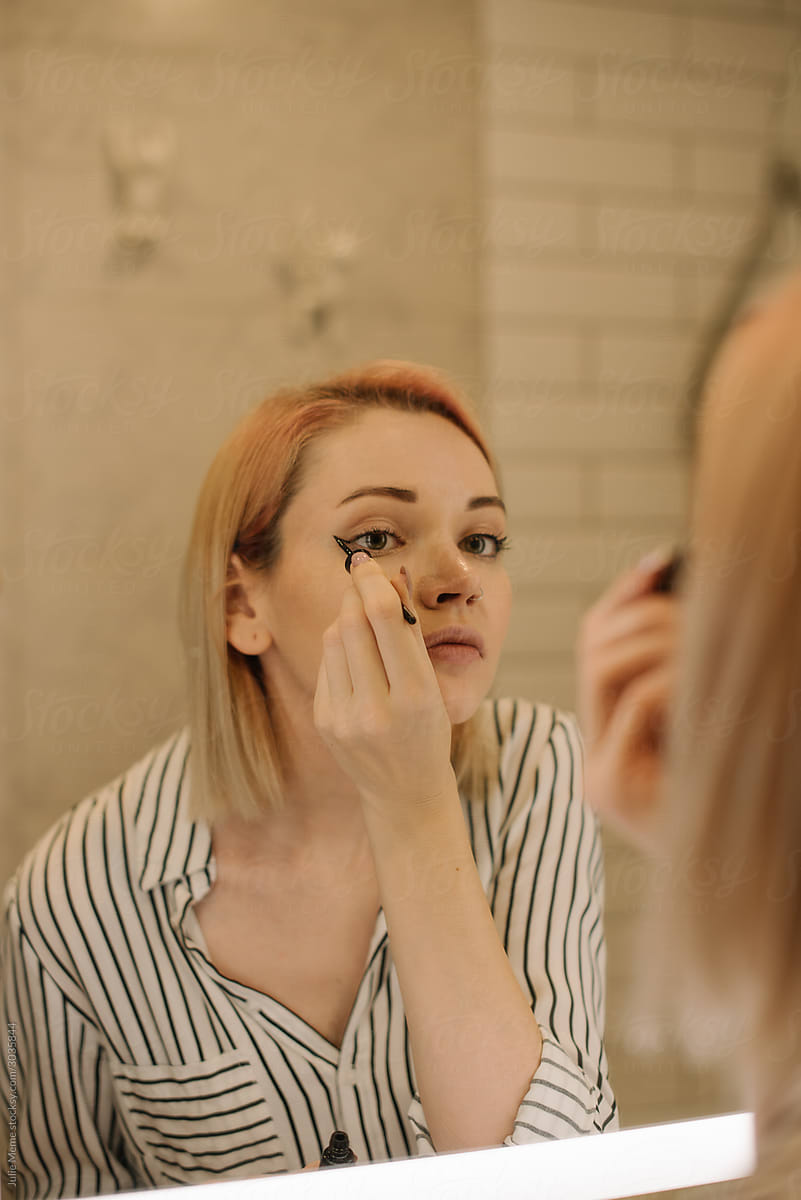 Girl does makeup in front of the mirror