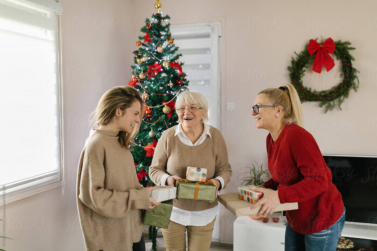 Cheerful women exchanging Christmas presents at home