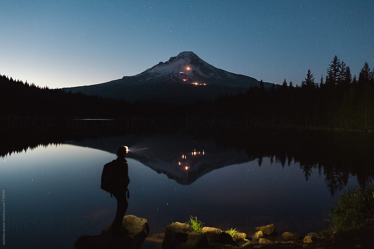 Woman walking along the river of Trillium Lake at night with head torch