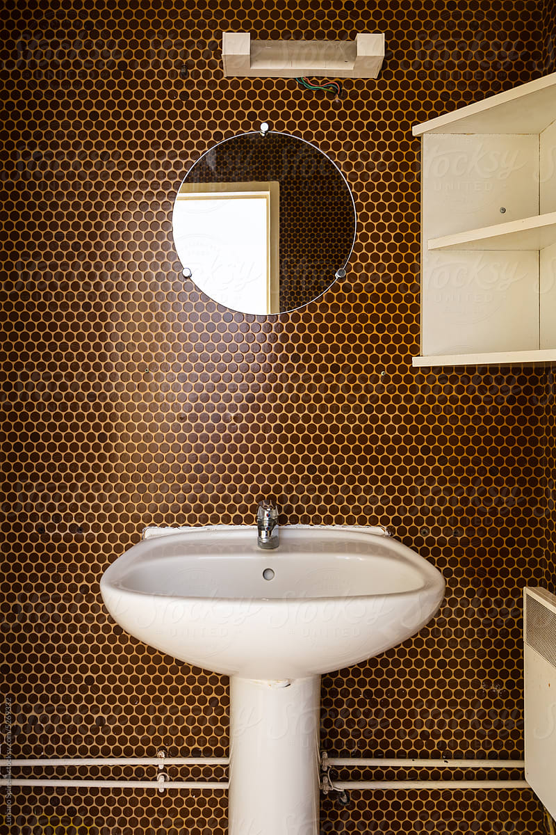 Minimalist toilet with polka dot wallpaper and white sink round mirror