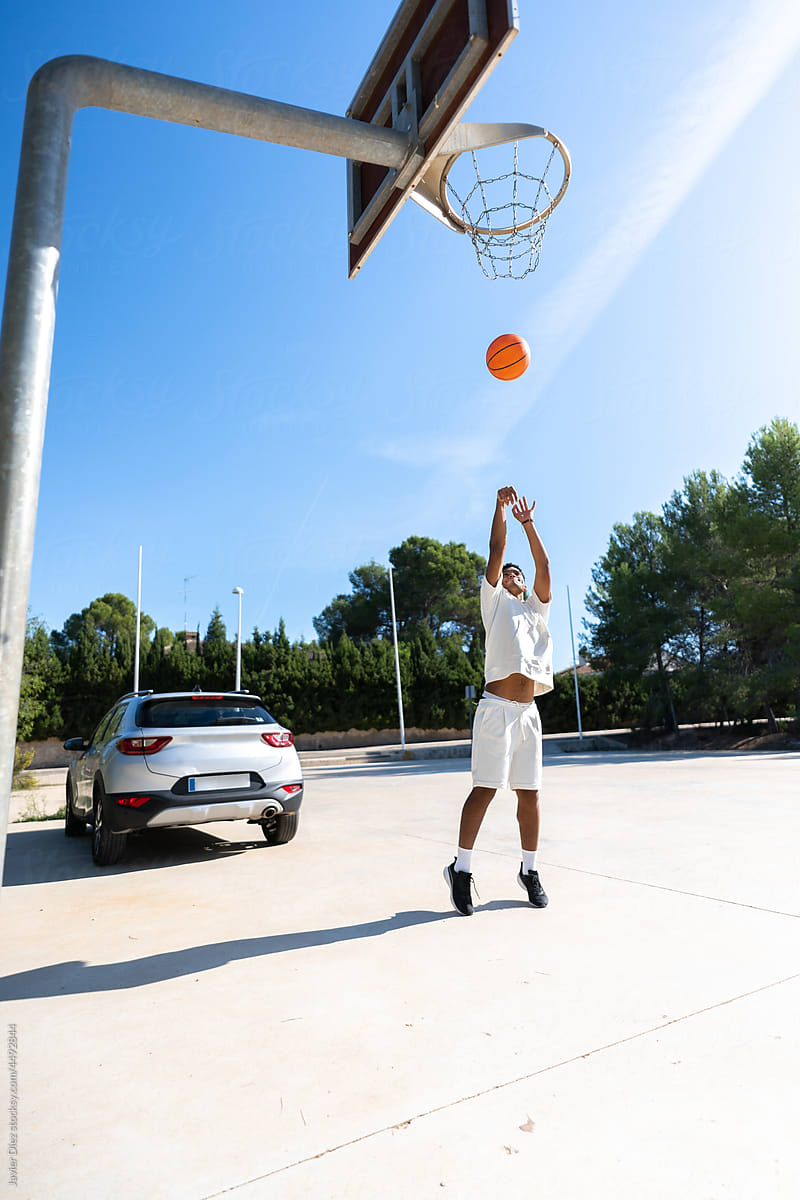 Sportsman playing basketball near car