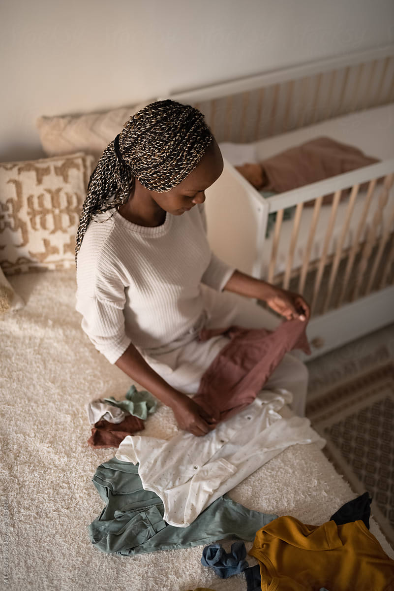 Focused black mother arranging clothes of baby