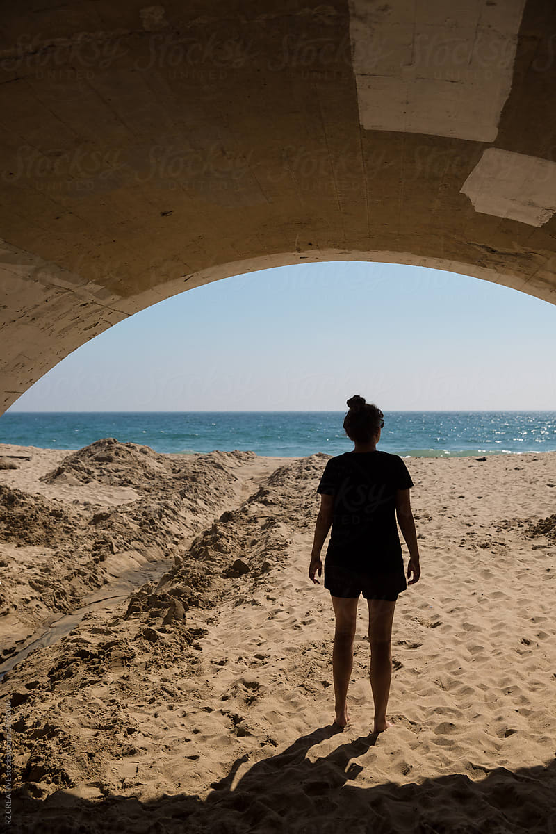 Woman standing at the end of a tunnel at the beach.