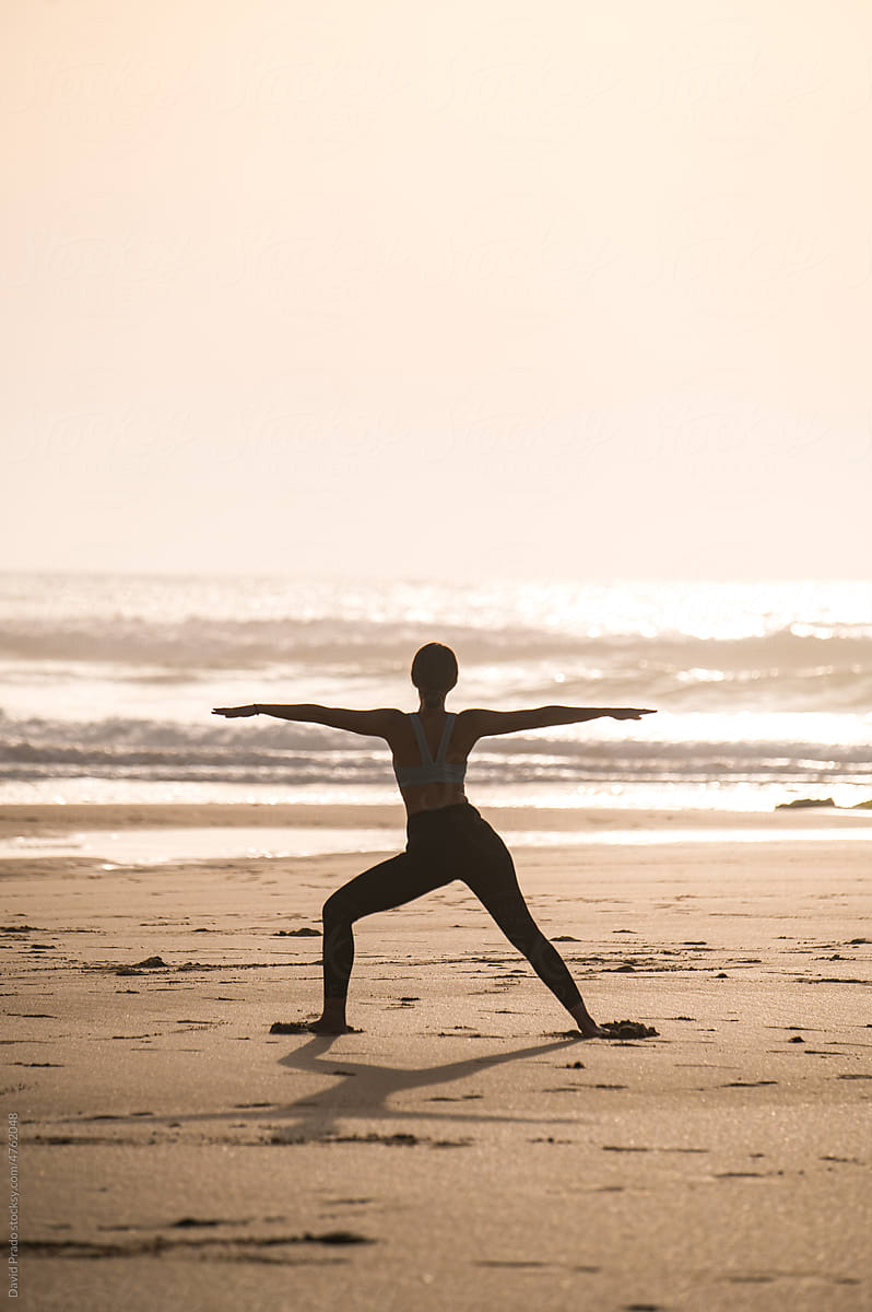 Unrecognizable woman stretching and doing yoga on beach