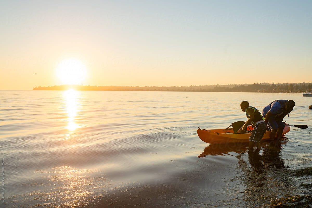 Father and son get into kayak at sunset