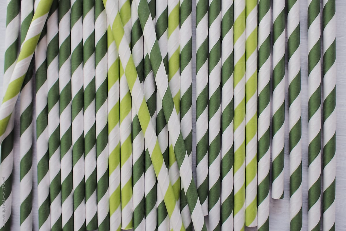 A group of striped green paper straws on a white kitchen table.