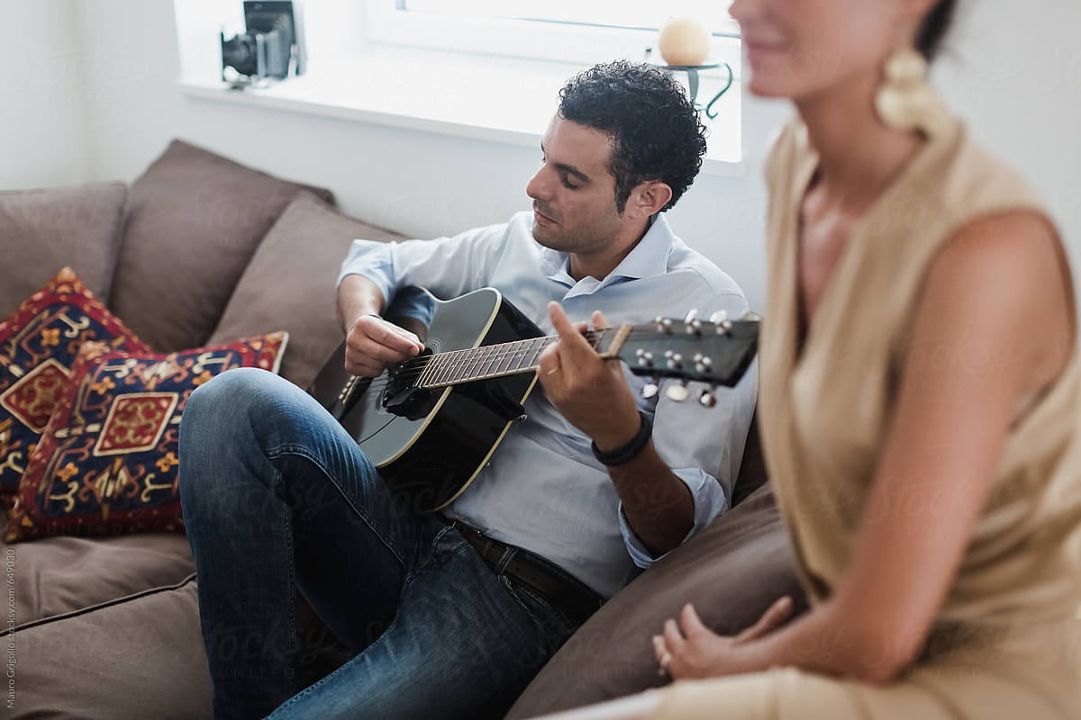 Man playing a song with an acoustic guitar at home
