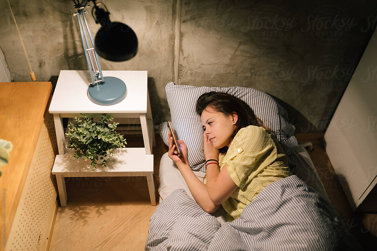 Young woman using her phone in bed