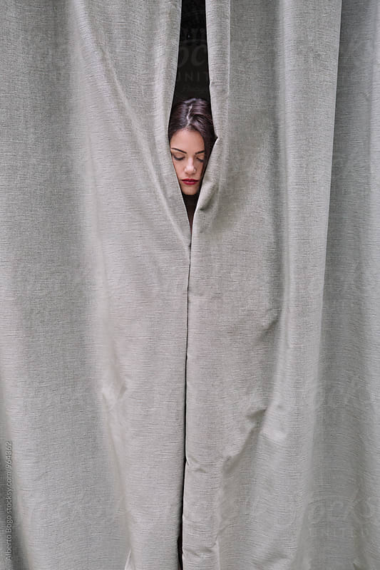 Woman face hiding behind the curtain.