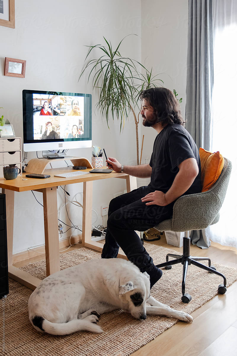 Young designer in video call in home office with dog