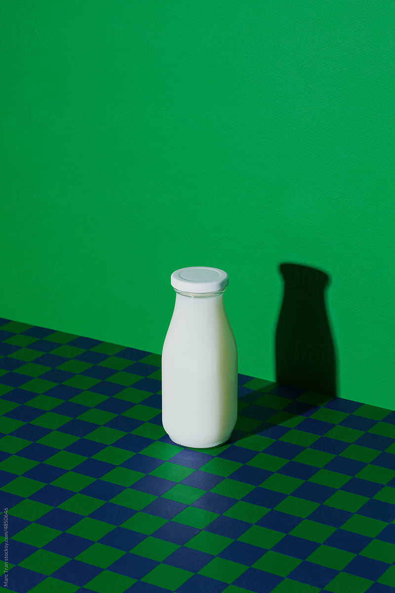 Milk in minimalism bottles on checkered against green background