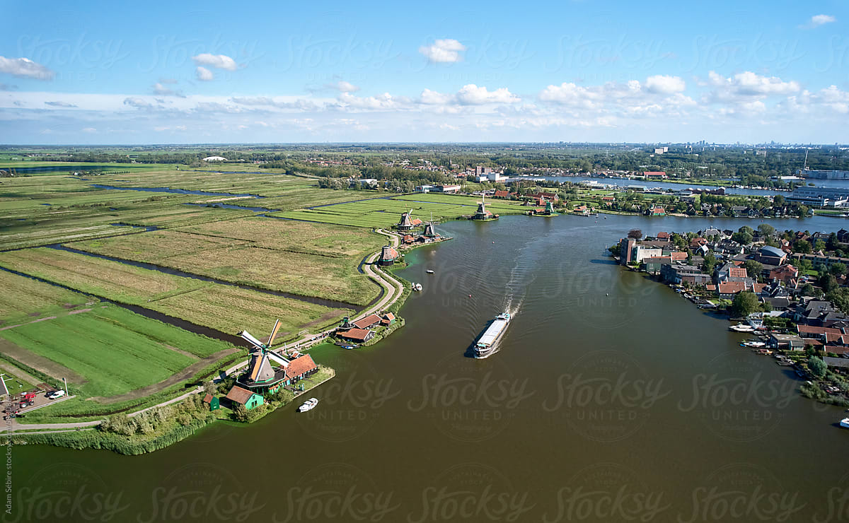 River barge cargo ship sails past Netherlands windmill, Zaandam