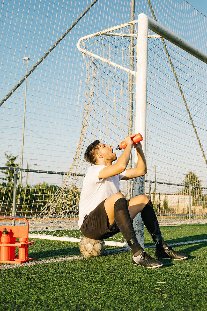 Soccer player drinking water near goal post