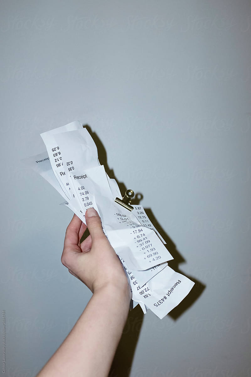 Hand holding a stack of paper receipt with paper clip with flashlight