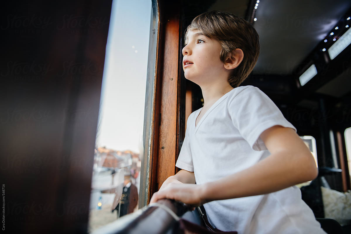 Boy looks out the window while riding on a train