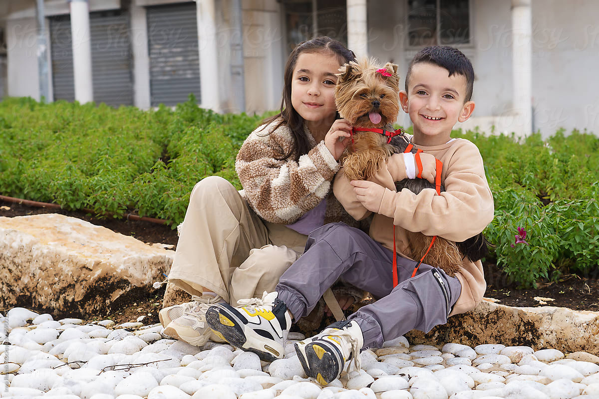 Siblings Embracing Cute Pet Dog Outdoors.