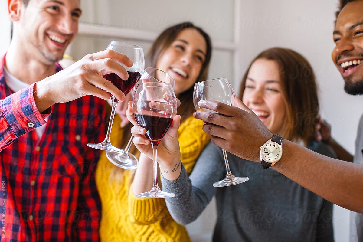 Group of happy young friends making a toast with glasses of red wine.