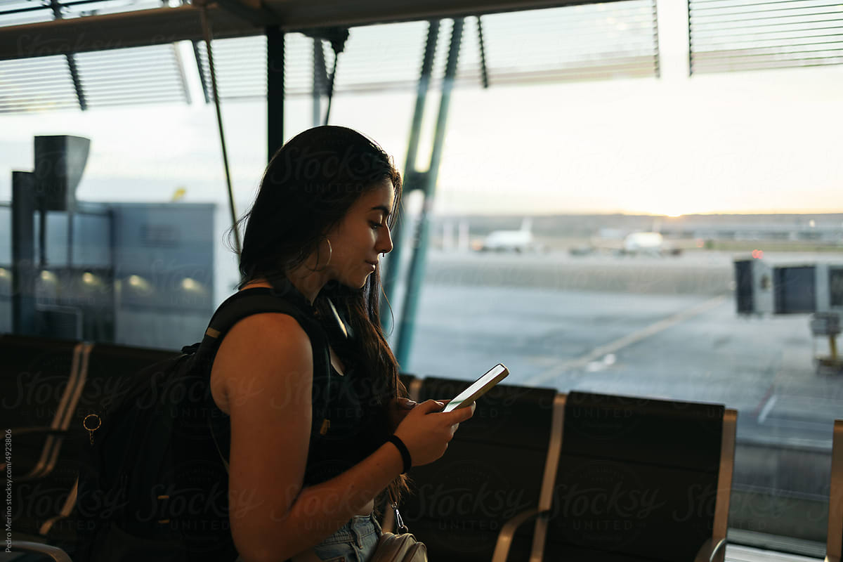 Woman at airport using smartphone waiting to board