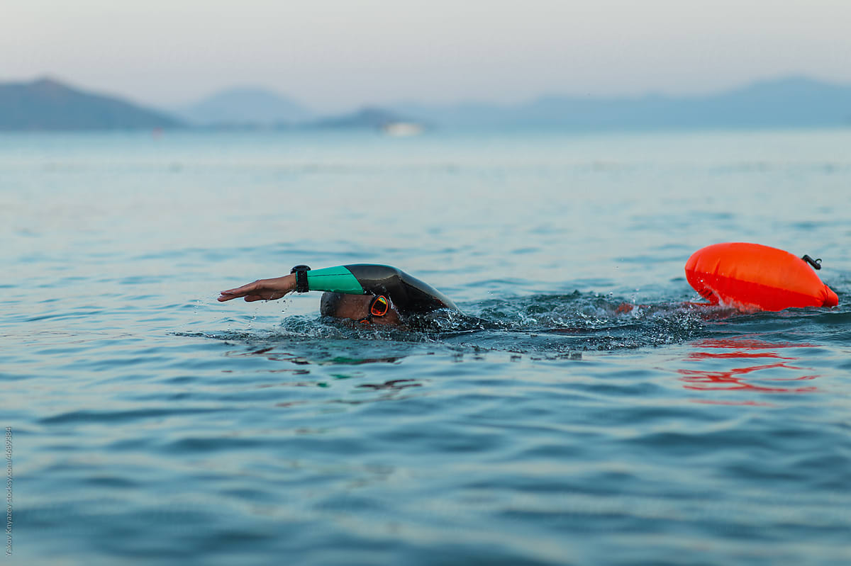 female swimming in the open water with a safety buoy