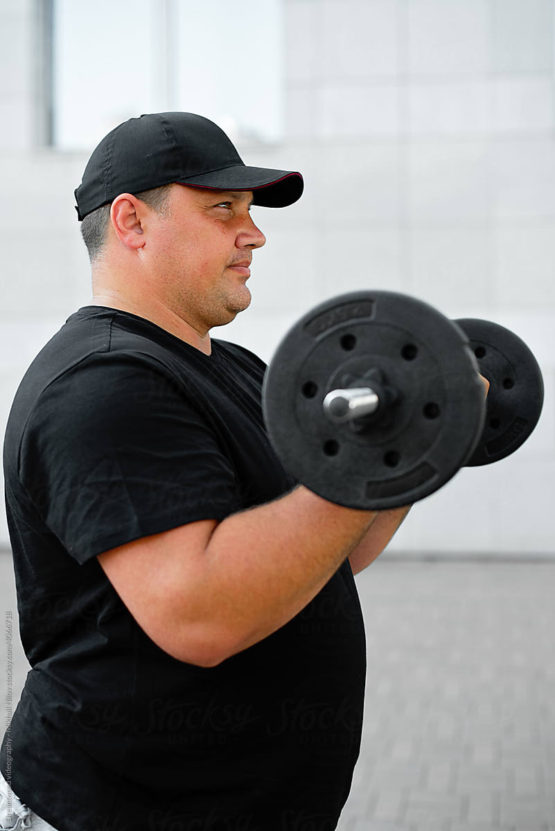 Fat man holding a barbell in his hands