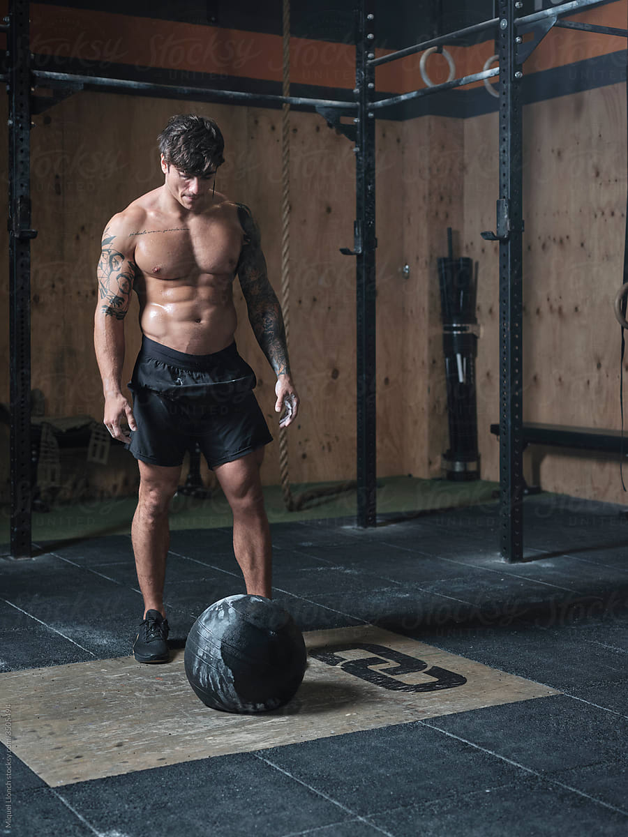 Young fit man with ball weightlifting