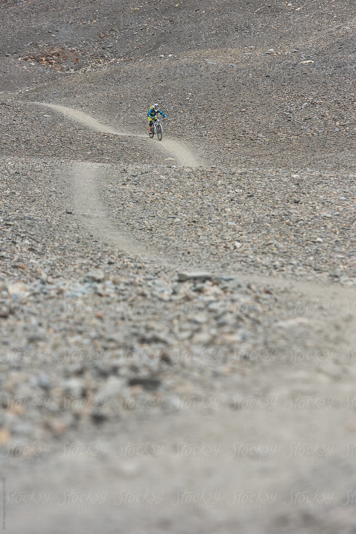 Anonymous person riding mountain bike downhill gravel singletrack