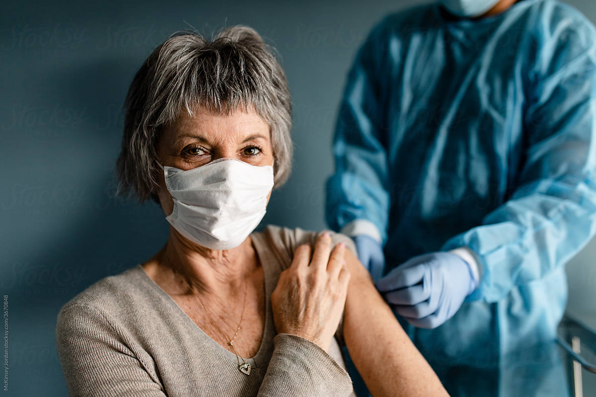 Nurse Puts Bandage on Older Woman After Vaccination