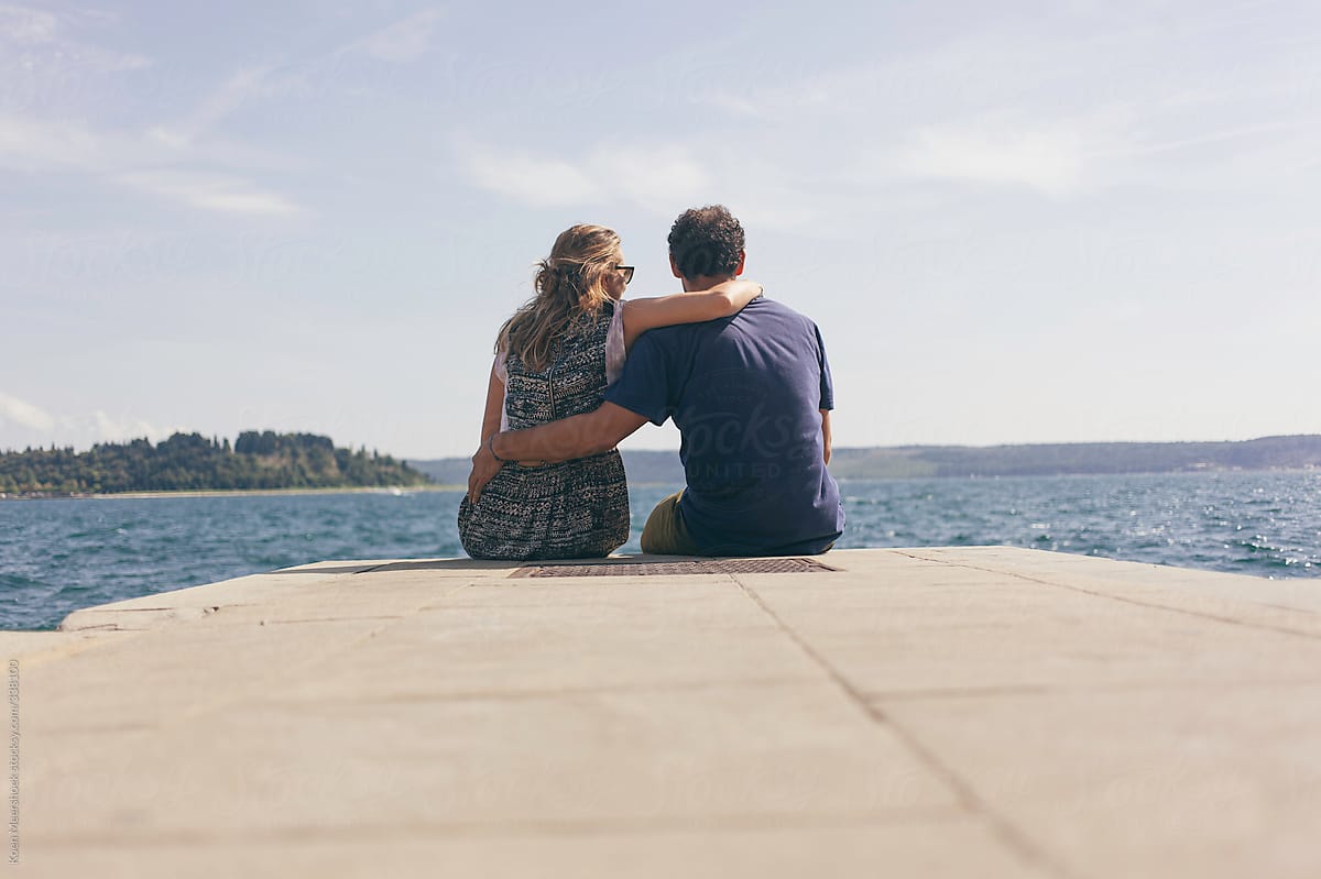 Couple In Love Sitting Arm In Arm Looking At The Sea On A Summer Day By Koen Meershoek Stocksy United