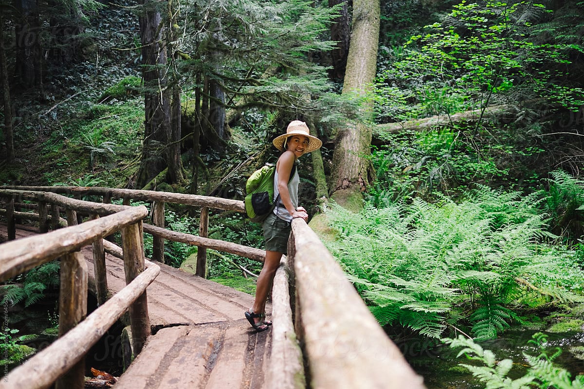 Woman resting on a bridge while on a hike in the forest