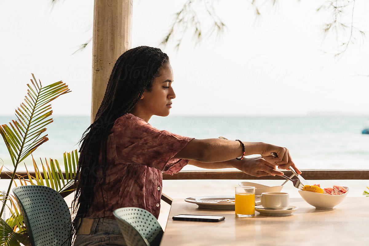 Black woman having breakfast on the beach