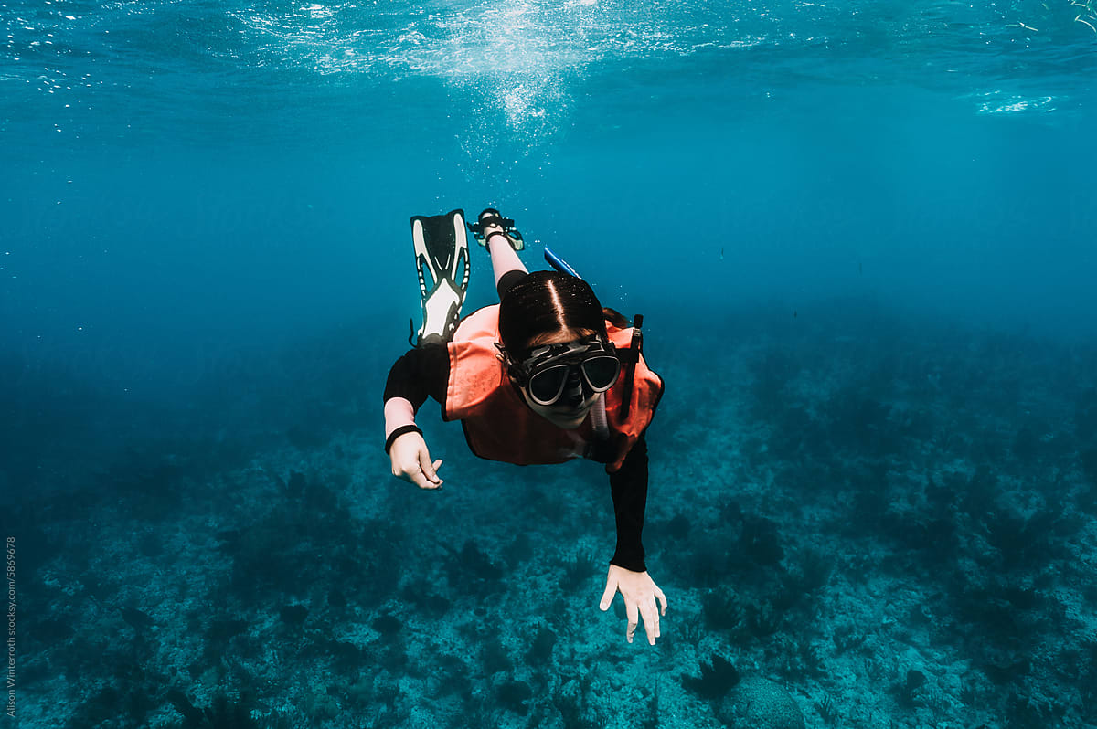 Girl explores ocean reef as she snorkels